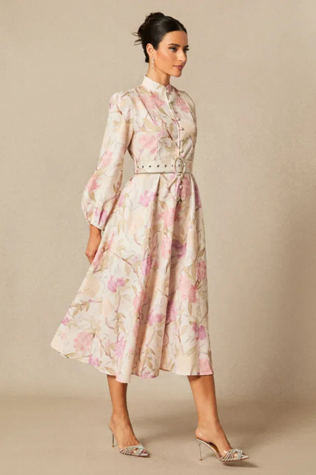 Side view of a woman modeling a floral print midi dress with puff sleeves and a belted waist. Secondary image