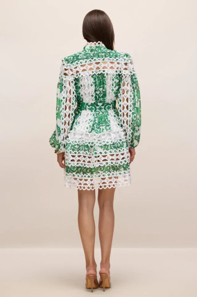 Back view of a woman wearing a green and white cut-out mini dress with long puff sleeves and lace trim.