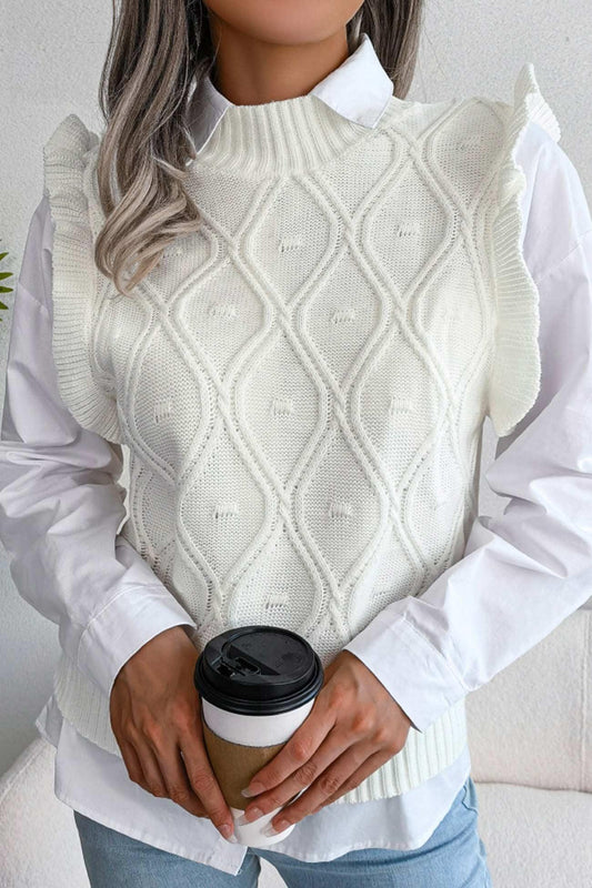 Woman holding a coffee cup while wearing a white cable knit sweater vest with ruffled shoulders over a white collared shirt.