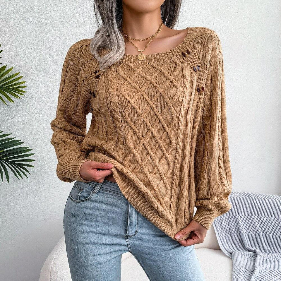 Woman wearing a tan cable knit sweater and blue jeans, lifting the hem of the sweater to show the fabric. Secondary image