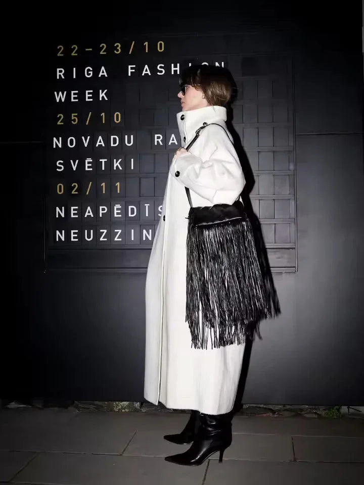 Woman in a white oversized wool blend coat and black accessories walking