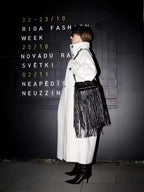 Woman in a white oversized wool blend coat and black accessories walking