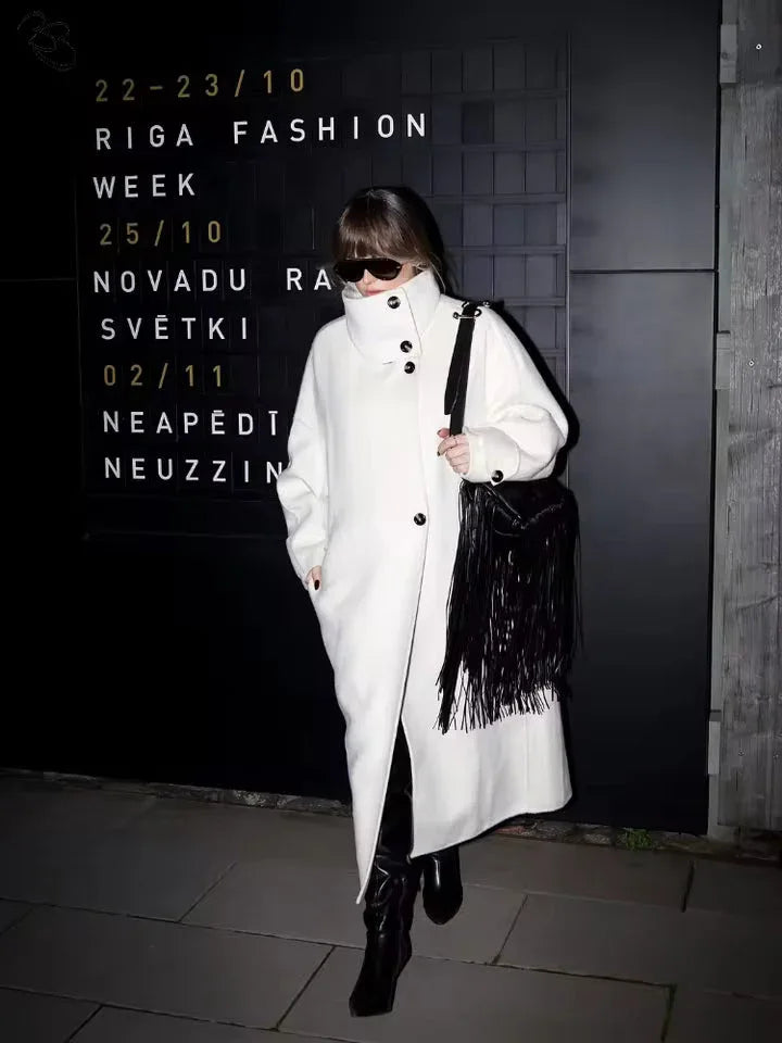 Woman in a white oversized wool blend coat with a black fringed bag