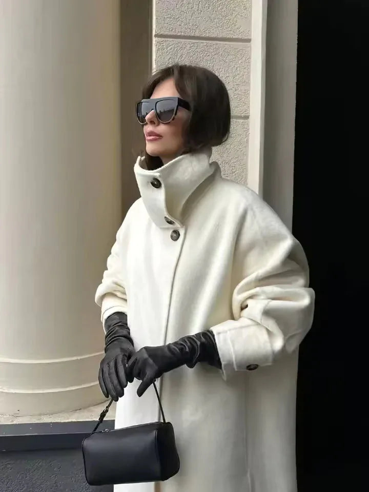 Close-up of a woman wearing a white oversized wool blend coat with a high neckline and black leather gloves