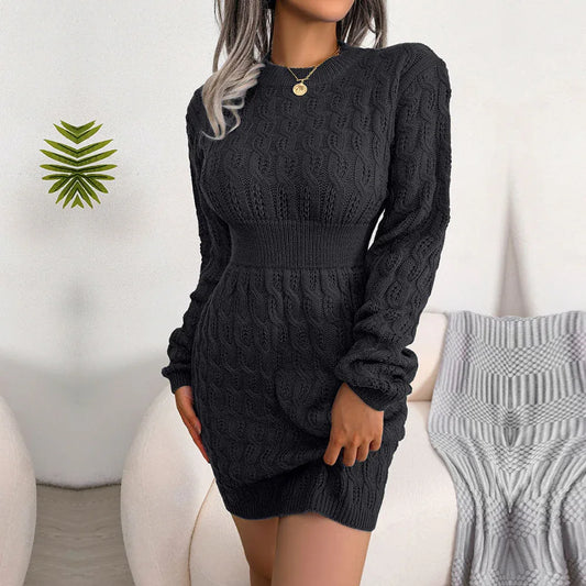 Woman wearing a black cable knit mini dress with long sleeves and a cinched waist.