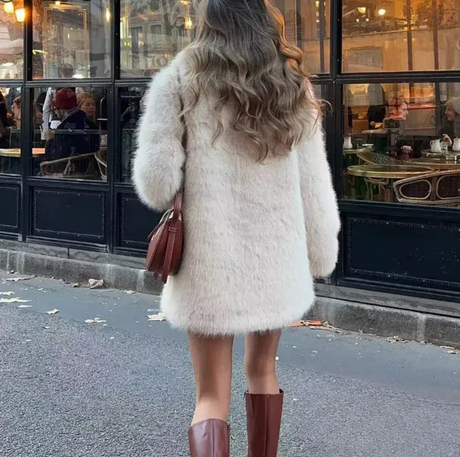 back view of a woman in a cream faux fur coat and brown boots