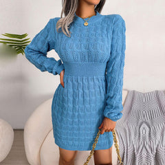 Woman holding a gold chain purse while wearing a blue knit dress.