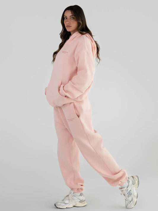 Full body shot of a woman in a light pink tracksuit