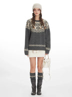 Woman wearing a grey and cream Fair Isle knit sweater, white mini skirt, grey knee-high socks, and black boots, front view