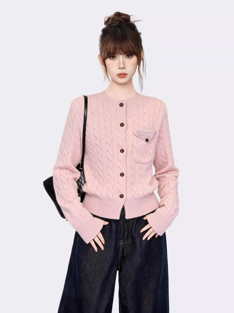 Woman wearing a pink cable knit cardigan with a crew neck and button-up closure, paired with dark wash wide-leg jeans and a black crossbody bag.
