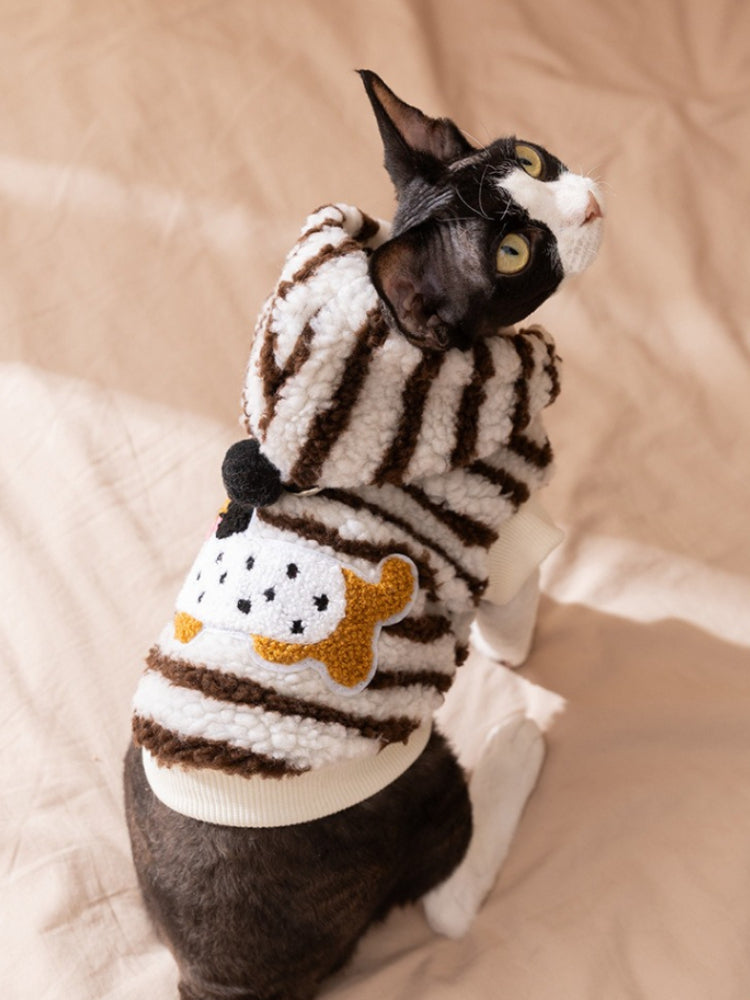 Sphynx cat wearing a brown and white striped sherpa fleece hoodie with a hood and a yellow applique on the back.