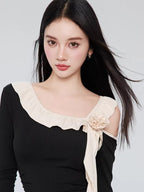 Close-up of the neckline of the black one-piece swimsuit, highlighting the ruffle trim and floral detail.