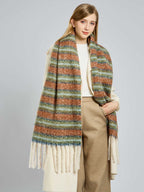 Woman modeling a cream coat and a long, wide striped scarf with tassels