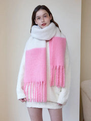 Woman wearing a white sweater and a white and pink two-tone fuzzy knit scarf with fringe trim.