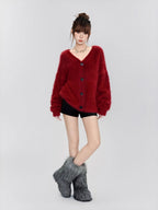 Full-body shot of a woman wearing a fuzzy red V-neck button-up cardigan, black shorts, and grey fuzzy boots.