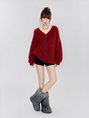 Full-body shot of a woman wearing a fuzzy red V-neck button-up cardigan, black shorts, and grey fuzzy boots.