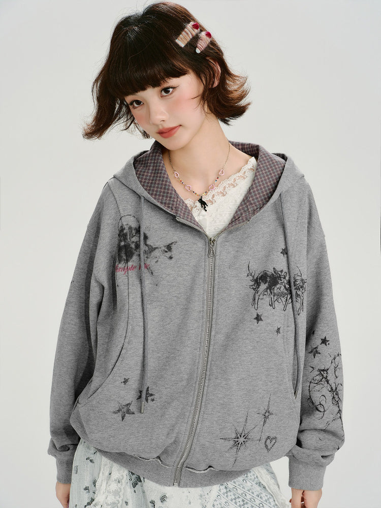 Front view of a young woman wearing a grey zip-up hoodie with a graphic print and a lace top, with the hood down.