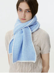 Woman looking forward, wearing a light blue ribbed knit scarf with white trim