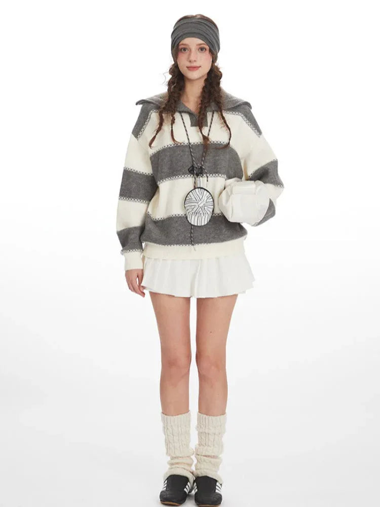 Model wearing a striped knit sweater with a white pleated skirt and cream leg warmers, front view