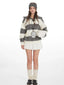 Model wearing a striped knit sweater with a white pleated skirt and cream leg warmers, front view