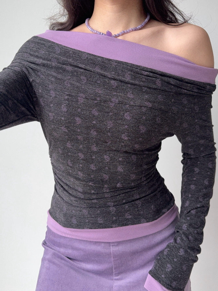 Close-up of a woman wearing a grey and purple off-the-shoulder long-sleeve top with a floral print.