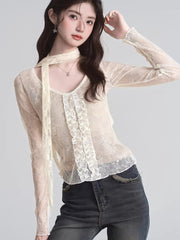 Front view of a woman in a cream lace top with ruffled front and a long scarf hanging down.