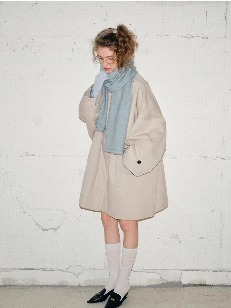 Full-body shot of the model wearing the beige oversized coat, light blue scarf, and matching gloves. She has on white knee-high socks and black loafers.