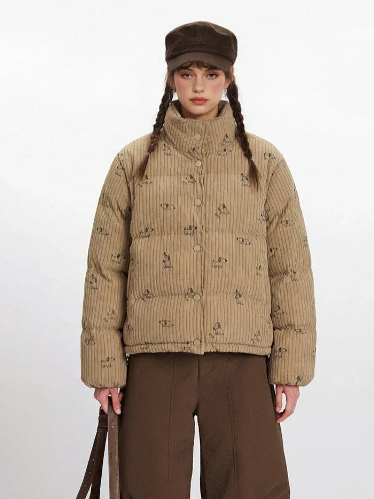 Front view of a woman wearing a tan corduroy puffer jacket with a repeating dog print, brown wide-leg pants, and a brown cap.