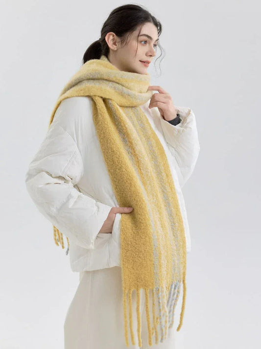 Woman wearing a yellow and gray striped scarf with fringe detail over a white puffer jacket