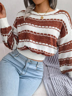 Close-up of a woman wearing a brown and white striped cropped knit sweater and light wash jeans.