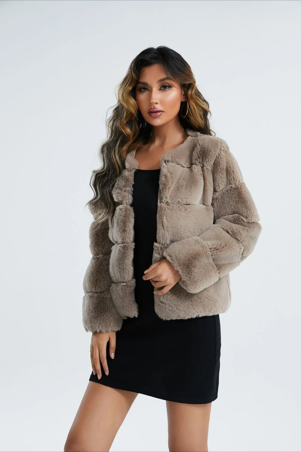 Woman wearing a taupe faux fur cropped jacket, holding a black handbag.