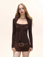 Close-up of a woman's torso wearing a brown long-sleeved top with a square neckline and bow detail, and a studded belt.