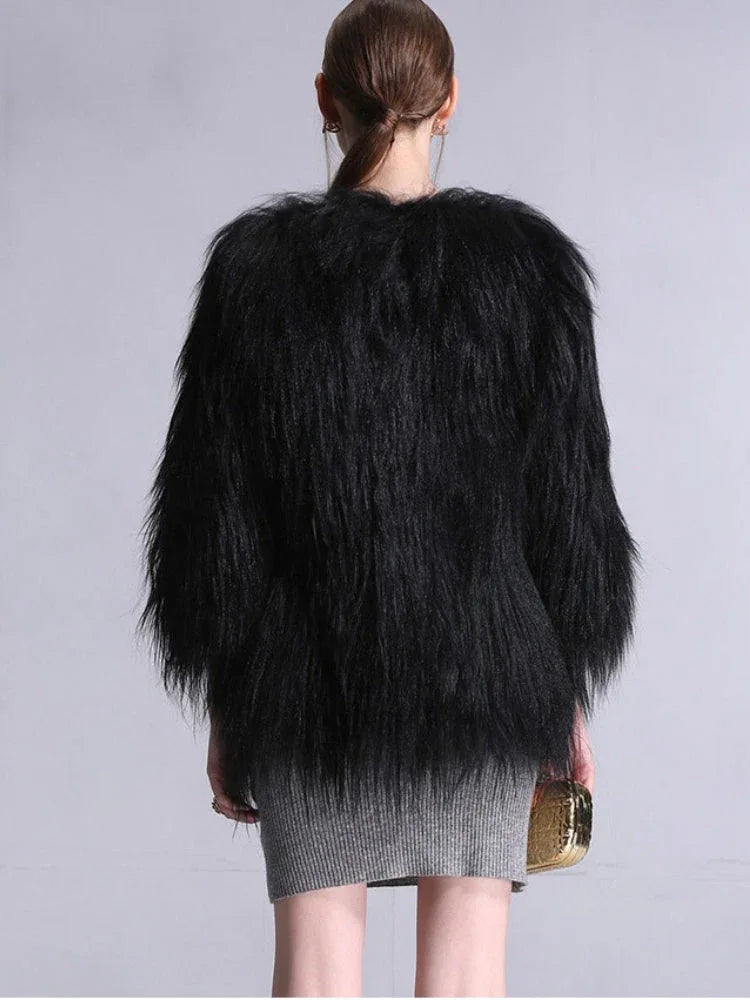 Back view of a woman wearing a black faux fur cropped jacket and a grey knit dress.