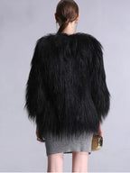 Back view of a woman wearing a black faux fur cropped jacket and a grey knit dress.