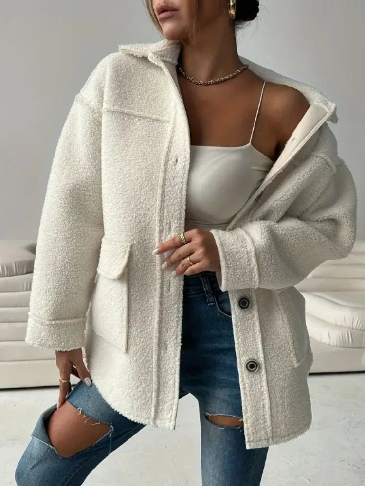 Front view of a woman wearing an oversized white sherpa fleece jacket, open to reveal a white crop top.