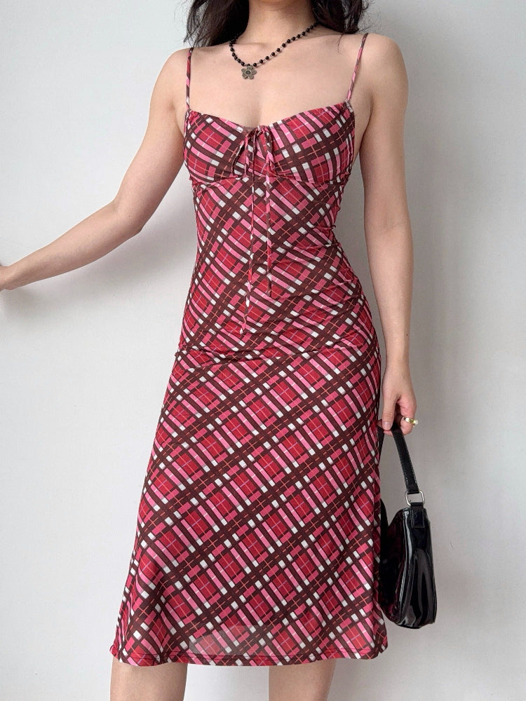 Side view of a woman modeling a red plaid midi dress with a sweetheart neckline and tie detail.