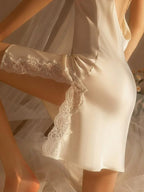 Close-up of a cream-colored satin slip dress with lace trim on the hem and side slit.