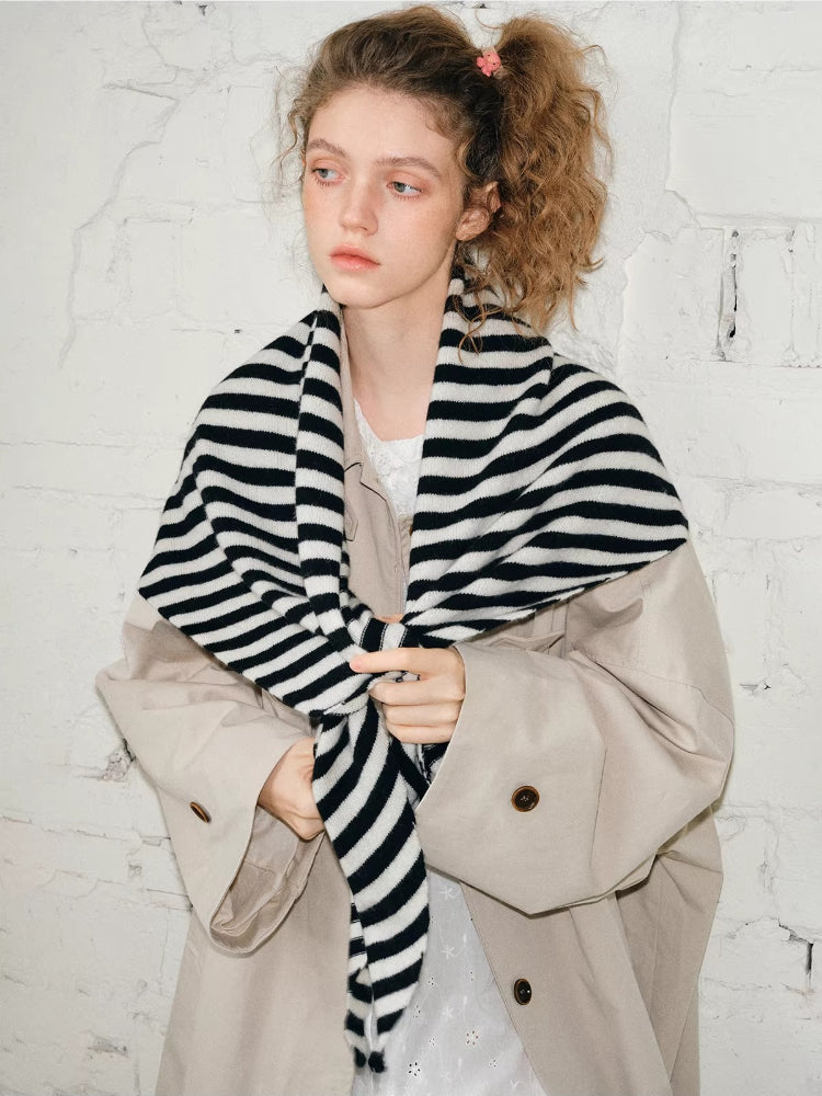 Close-up of a model tying a black and white striped scarf