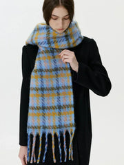Woman adjusting a blue and yellow plaid scarf with fringe