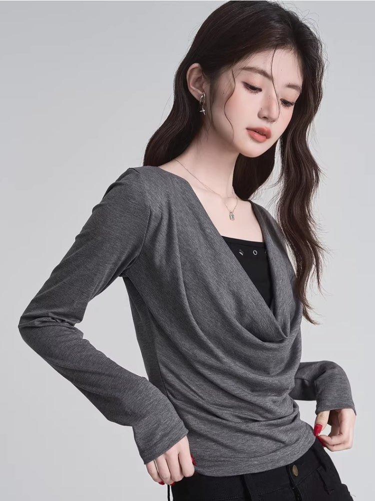 Close-up of a woman wearing a grey draped long-sleeve top over a black camisole.