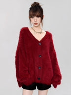 Close-up of a woman wearing a fuzzy red V-neck button-up cardigan.