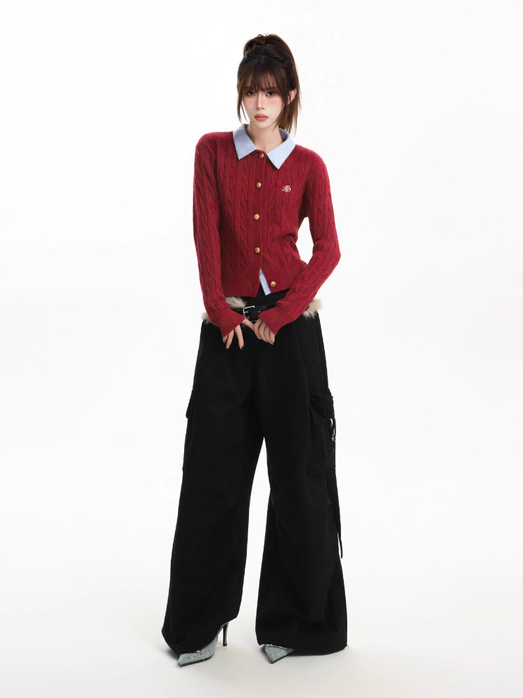 Full body shot of a woman in a red cable knit cardigan, light blue collared shirt, black cargo pants, and a furry belt.