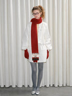 Model wearing a red scarf with a snowman design, red gloves, white jacket, and grey tights.