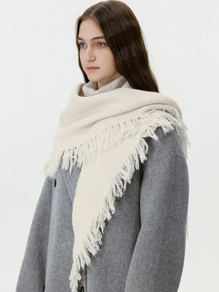 Close-up of a cream-colored fringed scarf draped around a model's neck