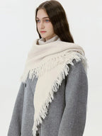 Close-up of a cream-colored fringed scarf draped around a model's neck
