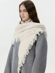 Close-up of a cream-colored fringed scarf draped around a model's neck