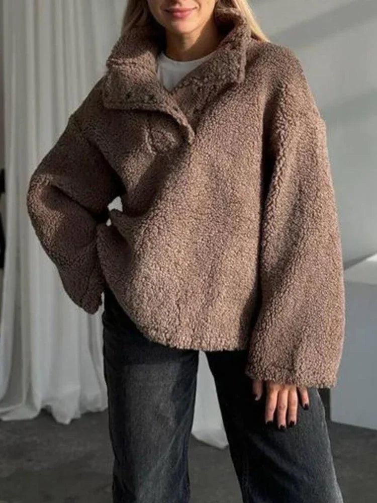Woman wearing a brown oversized fleece pullover with a stand-up collar and button closure.
