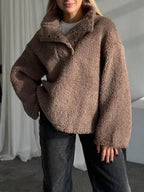 Woman wearing a brown oversized fleece pullover with a stand-up collar and button closure.
