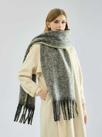 Close-up of a woman wearing a long, grey, textured knit scarf with fringe detail and lime green trim.