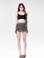 Woman wearing a black camisole and a striped ruched mini skirt.